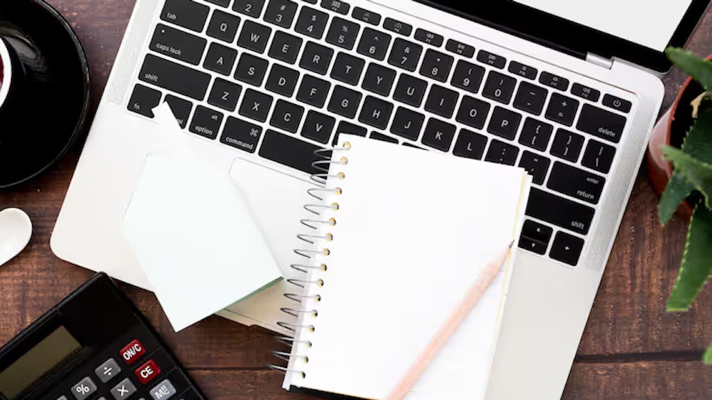 Leeres gewundenes Notizbuch mit Bleistift über einem offenen Laptop auf Holztisch