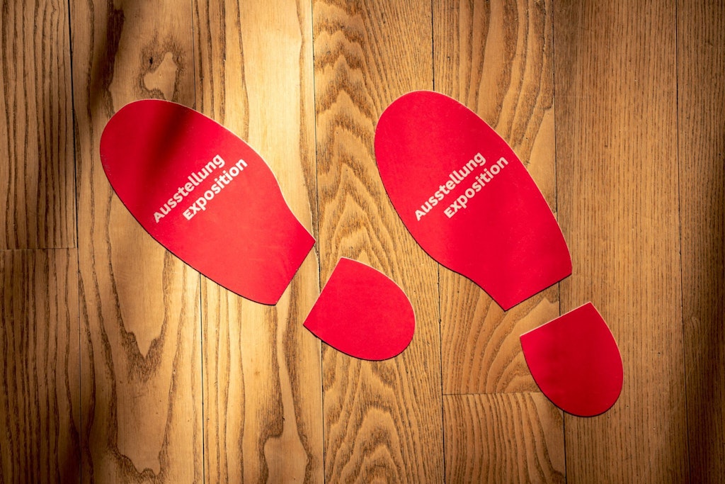 Auf dem Bild sind zwei Füsse auf dem Parkettboden zu sehen,