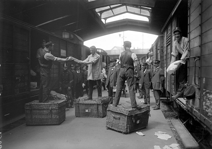 Auf dem Bild sieht man Postmitarbeiter beim Umladen der Pakete.