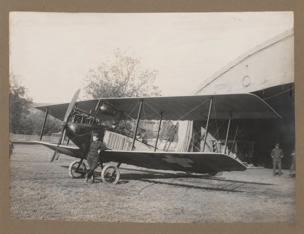 La fotografia mostra soldati delle truppe d’aviazione con un aereo davanti al padiglione di Schachen (Aarau), scattata intorno al 1914. Sotto le ali si vedono le croci svizzere, dipinte per evitare che gli aerei venissero colpiti accidentalmente. (Da: Hans Bandi (presumibilmente). Photos aviation dès 1914, BIG DU 555)